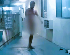 A naked man walks around an apartment complex.